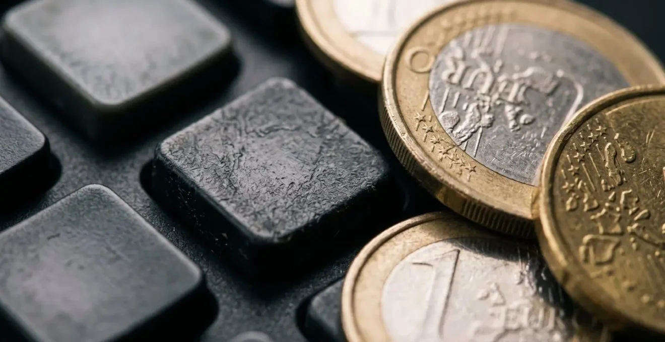 Vue macro détaillée d'une calculatrice avec des pièces de monnaie symbolisant le calcul du seuil de rentabilité